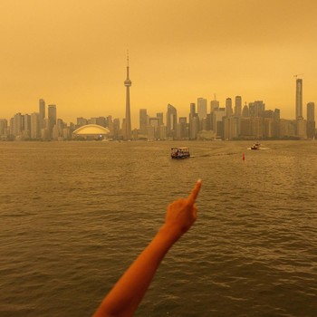 Seseorang menunjuk ke cakrawala saat menaiki feri dari Pulau Toronto, sementara asap kebakaran hutan dari Ontario barat laut memenuhi langit, ditambah dengan gelombang panas yang hebat, memicu peringatan kesehatan dan seruan kepada warga untuk membat