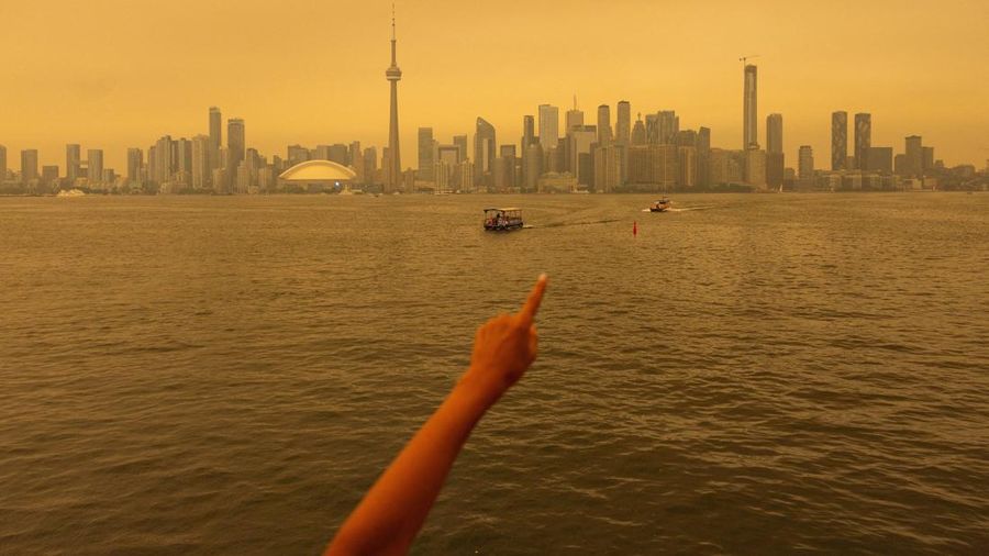 Seseorang menunjuk ke cakrawala saat menaiki feri dari Pulau Toronto, sementara asap kebakaran hutan dari Ontario barat laut memenuhi langit, ditambah dengan gelombang panas yang hebat, memicu peringatan kesehatan dan seruan kepada warga untuk membat