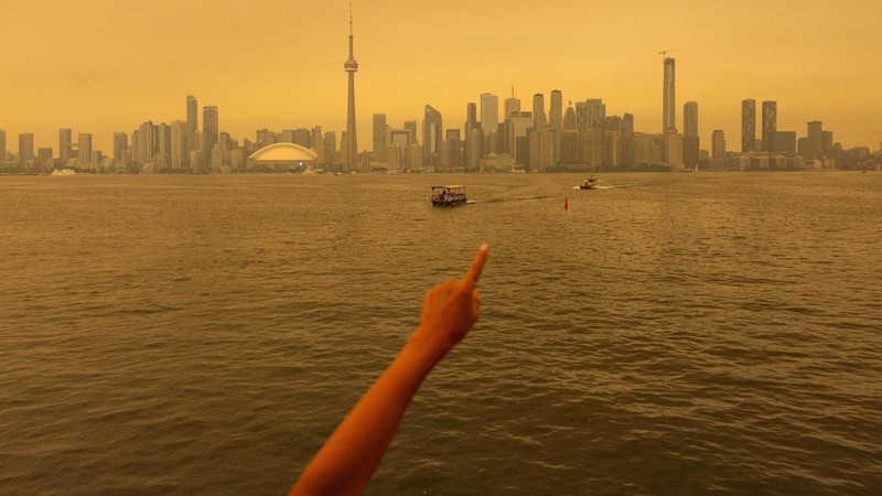Seseorang menunjuk ke cakrawala saat menaiki feri dari Pulau Toronto, sementara asap kebakaran hutan dari Ontario barat laut memenuhi langit, ditambah dengan gelombang panas yang hebat, memicu peringatan kesehatan dan seruan kepada warga untuk membat