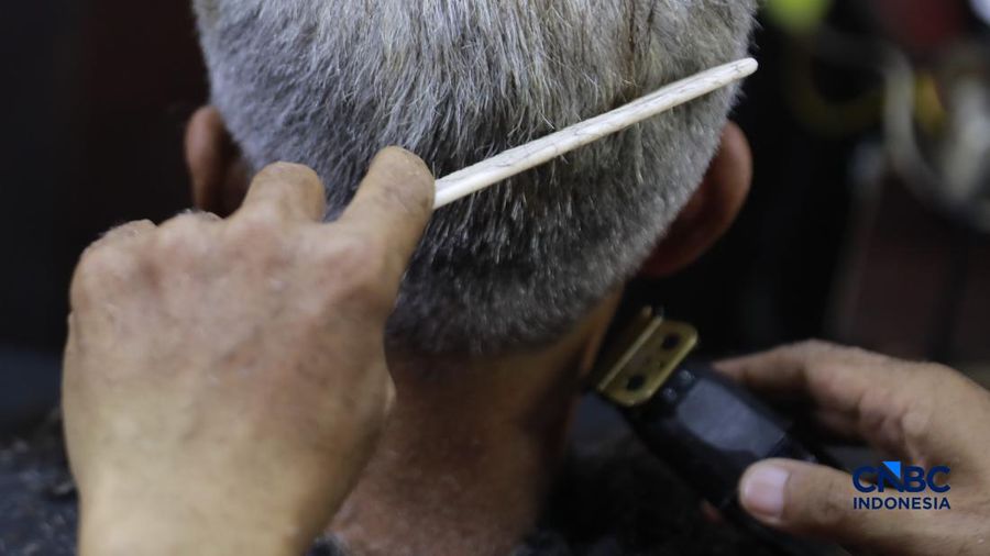 Supri 62 tahun pemilik jasa cukur rambut melayani pelanggan di Kawasan jalan Pemuda, Bogor, Jawa Barat, Kamis, (16/7/2026). (CNBC Indonesia/Muhammad Sabki)