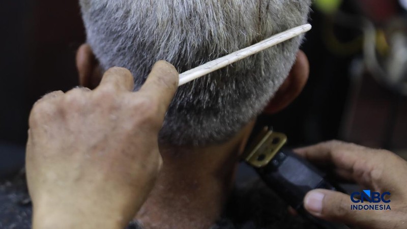Supri 62 tahun pemilik jasa cukur rambut melayani pelanggan di Kawasan jalan Pemuda, Bogor, Jawa Barat, Kamis, (16/7/2026). (CNBC Indonesia/Muhammad Sabki)