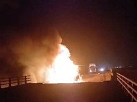 Api berkobar di jembatan yang rusak akibat serangan udara, di Bandar Khamir, provinsi Hormozgan, Iran, 16 Juli 2026, dalam cuplikan layar yang diperoleh dari video media sosial. (Media Sosial/via REUTERS)