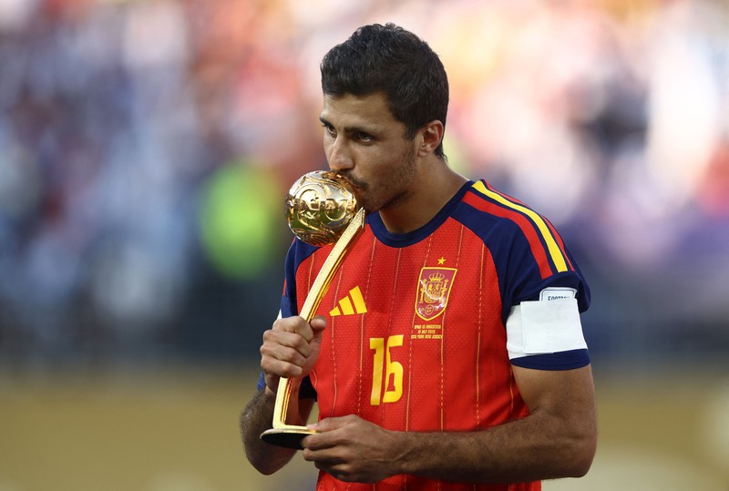 Kapten Spanyol Rodri merayakan penghargaan Bola Emas (Golden Ball) di podium bersama kiper Unai Simon yang meraih Sarung Tangan Emas (Golden Glove) dan bek Pau Cubarsi yang dinobatkan sebagai Pemain Muda Terbaik, usai membawa Spanyol menjuarai Piala Dunia FIFA 2026 di New York/New Jersey Stadium, East Rutherford, New Jersey, Amerika Serikat, Minggu (19/7/2026). (REUTERS/Mike Segar)