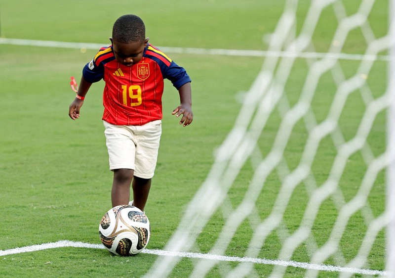 Lamine Yamal merayakan keberhasilan Spanyol menjuarai Piala Dunia FIFA 2026, sementara adiknya, Keyne Yamal, bermain sepak bola di lapangan usai seremoni penyerahan trofi di New York/New Jersey Stadium, East Rutherford, New Jersey, Amerika Serikat, Minggu (19/7/2026). (REUTERS/Agustin Marcarian)