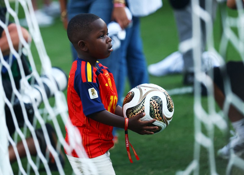 Lamine Yamal merayakan keberhasilan Spanyol menjuarai Piala Dunia FIFA 2026, sementara adiknya, Keyne Yamal, bermain sepak bola di lapangan usai seremoni penyerahan trofi di New York/New Jersey Stadium, East Rutherford, New Jersey, Amerika Serikat, Minggu (19/7/2026). (REUTERS/Agustin Marcarian)