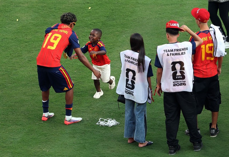 Lamine Yamal merayakan keberhasilan Spanyol menjuarai Piala Dunia FIFA 2026, sementara adiknya, Keyne Yamal, bermain sepak bola di lapangan usai seremoni penyerahan trofi di New York/New Jersey Stadium, East Rutherford, New Jersey, Amerika Serikat, Minggu (19/7/2026). (REUTERS/Agustin Marcarian)