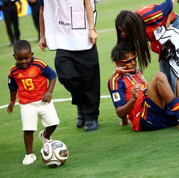 Lamine Yamal merayakan keberhasilan Spanyol menjuarai Piala Dunia FIFA 2026, sementara adiknya, Keyne Yamal, bermain sepak bola di lapangan usai seremoni penyerahan trofi di New York/New Jersey Stadium, East Rutherford, New Jersey, Amerika Serikat, M