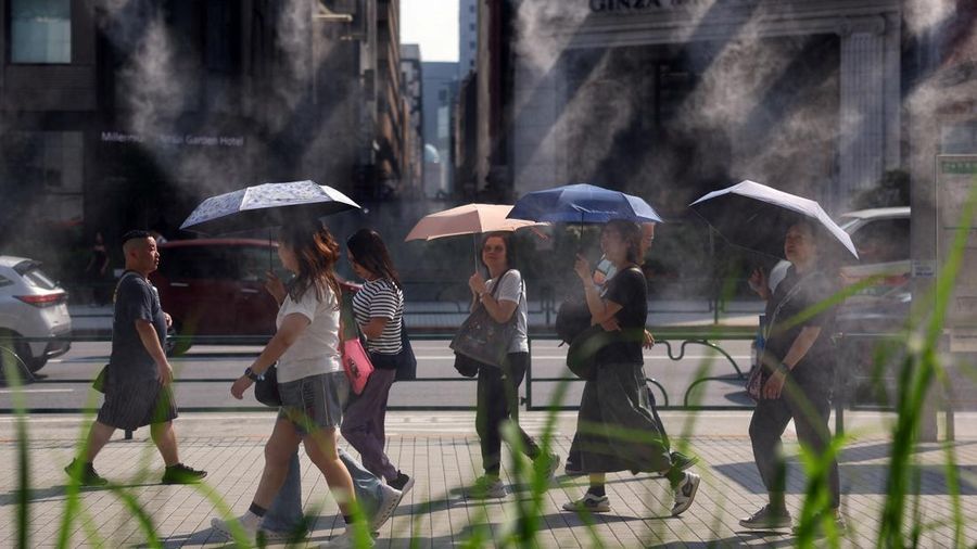 Orang-orang yang membawa payung berjalan di dekat kabut yang menyejukkan saat pemerintah Jepang mengeluarkan peringatan serangan panas di Tokyo dan prefektur lainnya karena gelombang panas, di Tokyo, Jepang, 22 Juli 2026.