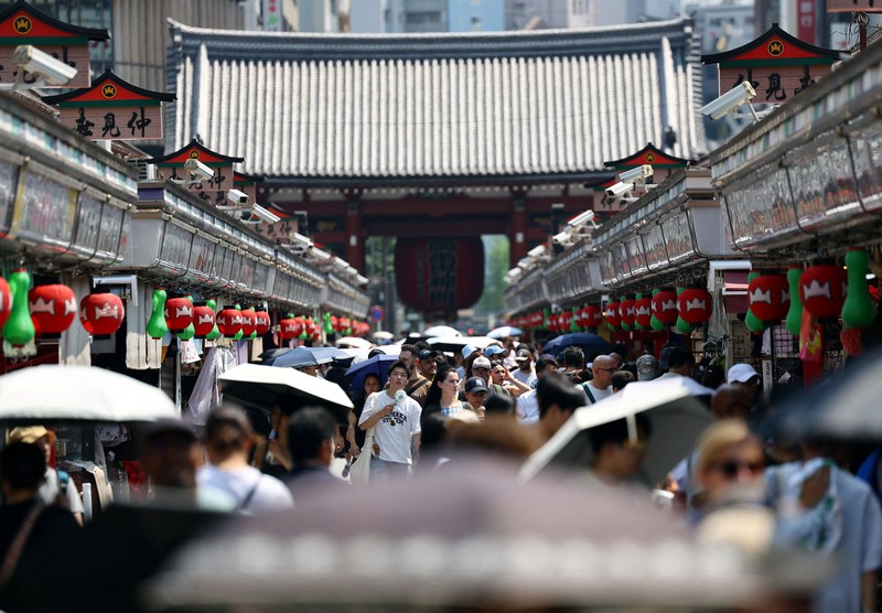 Seorang pengunjung beristirahat di dekat kabut pendingin di depan pagoda lima lantai di kuil Sensoji, tempat wisata populer, saat pemerintah Jepang mengeluarkan peringatan serangan panas di Tokyo dan prefektur lainnya karena gelombang panas, di Tokyo, Jepang, 22 Juli 2026. (REUTERS/Issei Kato)