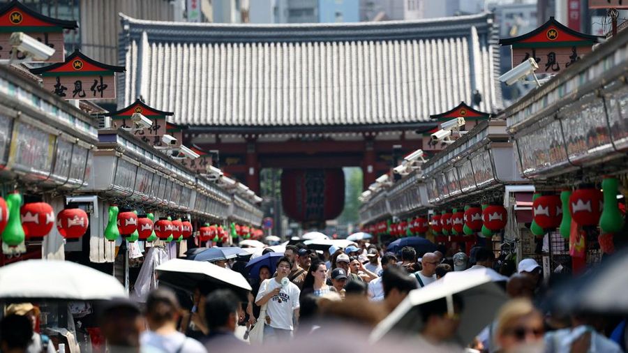 Para pengunjung yang membawa payung berjalan di sepanjang Jalan Nakamise di distrik Asakusa, sebuah tempat wisata populer, saat pemerintah Jepang mengeluarkan peringatan serangan panas di Tokyo dan prefektur lainnya karena gelombang panas, di Tokyo, Jepang, 22 Juli 2026.