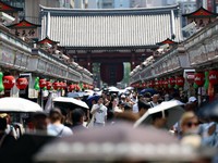 Para pengunjung yang membawa payung berjalan di sepanjang Jalan Nakamise di distrik Asakusa, sebuah tempat wisata populer, saat pemerintah Jepang mengeluarkan peringatan serangan panas di Tokyo dan prefektur lainnya karena gelombang panas, di Tokyo,