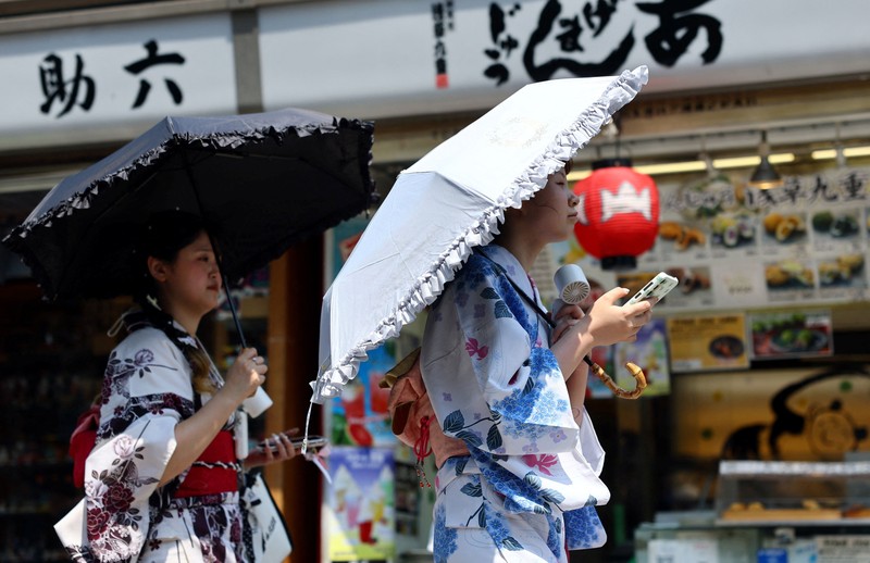 Seorang pengunjung beristirahat di dekat kabut pendingin di depan pagoda lima lantai di kuil Sensoji, tempat wisata populer, saat pemerintah Jepang mengeluarkan peringatan serangan panas di Tokyo dan prefektur lainnya karena gelombang panas, di Tokyo, Jepang, 22 Juli 2026. (REUTERS/Issei Kato)