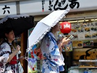 Para wanita yang mengenakan yukata, atau kimono kasual musim panas, menggunakan kipas portabel saat mereka berjalan di sepanjang Jalan Nakamise di distrik Asakusa, Tokyo, Jepang, 22 Juli 2026. (REUTERS/Issei Kato)