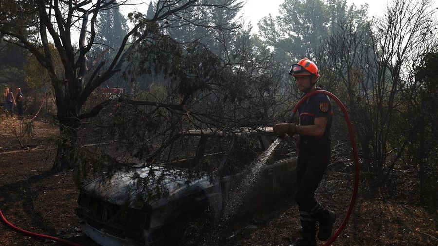 Petugas pemadam kebakaran Prancis menyemprotkan air di dekat mobil yang terbakar selama operasi pembersihan di dekat sebuah rumah yang terbakar di daerah yang terkena dampak kebakaran hutan di Cotignac, di departemen Var, saat kondisi kekeringan memburuk setelah gelombang panas dan kekurangan air di sebagian besar Prancis, 22 Juli 2026.