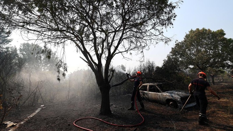 Petugas pemadam kebakaran Prancis menyemprotkan air selama operasi pembersihan di dekat sebuah rumah dan mobil yang terbakar di daerah yang terkena dampak kebakaran hutan di Cotignac, departemen Var, saat kondisi kekeringan memburuk setelah gelombang panas dan kekurangan air di sebagian besar wilayah Prancis, 22 Juli 2026.