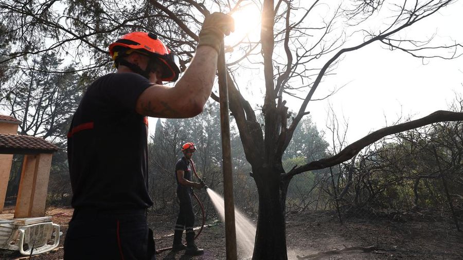 Petugas pemadam kebakaran Prancis menyemprotkan air selama operasi pembersihan di dekat sebuah rumah yang terbakar di daerah yang terkena dampak kebakaran hutan di Cotignac, di departemen Var, saat kondisi kekeringan memburuk setelah gelombang panas dan kekurangan air di sebagian besar Prancis, 22 Juli 2026.