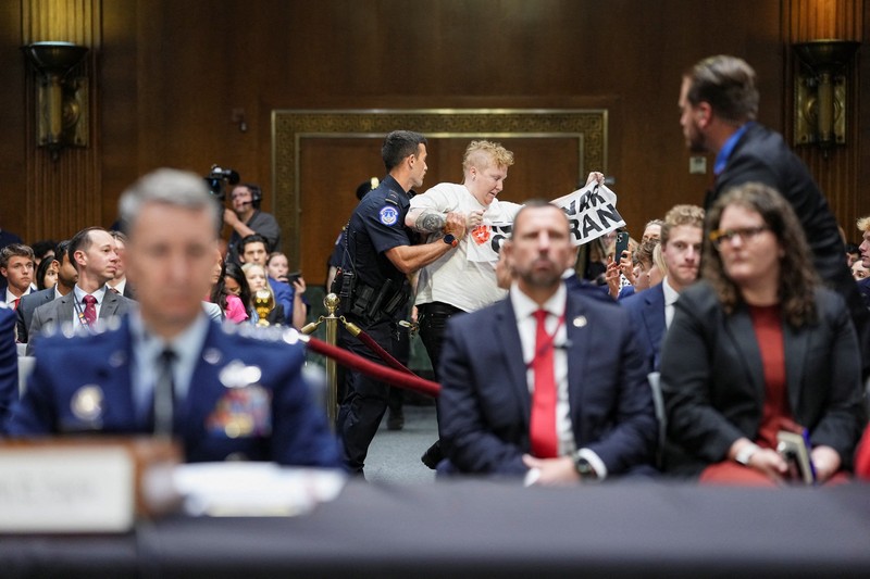 Seorang demonstran berdiri dan membentangkan poster menolak perang terhadap Iran saat sidang Komite Alokasi Anggaran Senat mengenai permintaan pendanaan tambahan Presiden AS Donald Trump untuk Departemen Pertahanan, di Washington, D.C., AS, Selasa (21/7/2026),