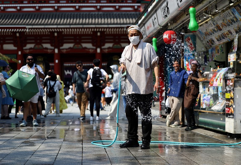 Seorang pengunjung beristirahat di dekat kabut pendingin di depan pagoda lima lantai di kuil Sensoji, tempat wisata populer, saat pemerintah Jepang mengeluarkan peringatan serangan panas di Tokyo dan prefektur lainnya karena gelombang panas, di Tokyo, Jepang, 22 Juli 2026. (REUTERS/Issei Kato)
