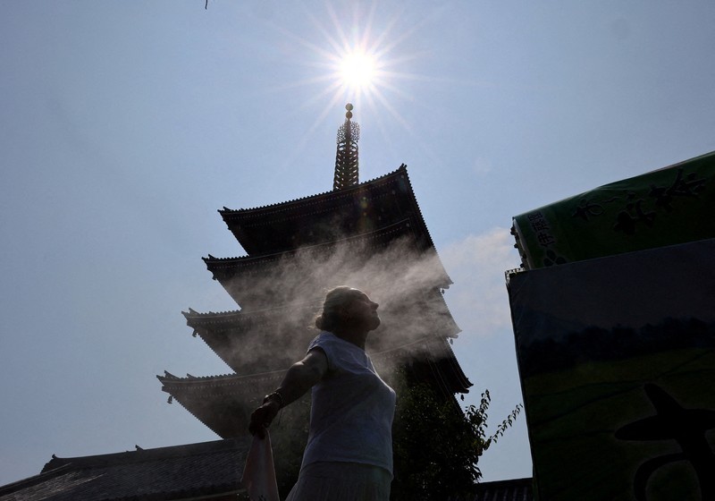Seorang pengunjung beristirahat di dekat kabut pendingin di depan pagoda lima lantai di kuil Sensoji, tempat wisata populer, saat pemerintah Jepang mengeluarkan peringatan serangan panas di Tokyo dan prefektur lainnya karena gelombang panas, di Tokyo, Jepang, 22 Juli 2026. (REUTERS/Issei Kato)