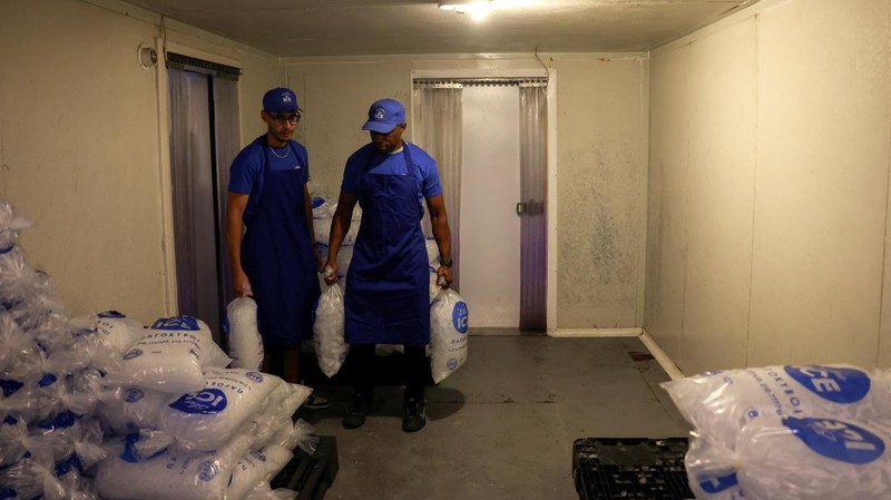 Karyawan Blue Ice, Aziz Lasnami dan Evans Osagie, membawa kantong-kantong es batu di fasilitas perusahaan selama gelombang panas di Athena, Yunani, 22 Juli 2026.