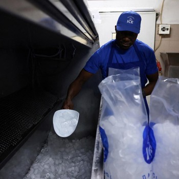 Karyawan Blue Ice, Evans Osagie, memasukkan es batu ke dalam kantong saat gelombang panas di Athena, Yunani, 22 Juli 2026. (REUTERS/Louiza Vradi)