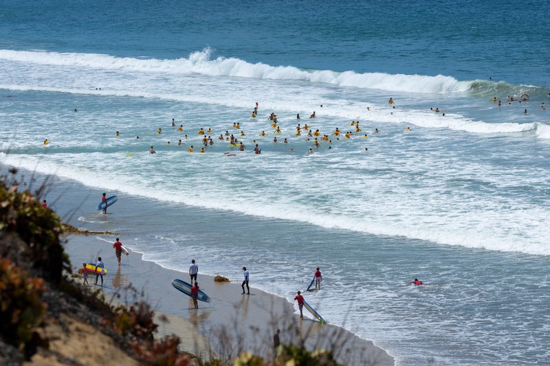 Sebuah tayangan drone memperlihatkan orang-orang menikmati air hangat di lautan sepanjang garis pantai di Encinitas, California, AS, 21 Juli 2026. (REUTERS/Mike Blake)