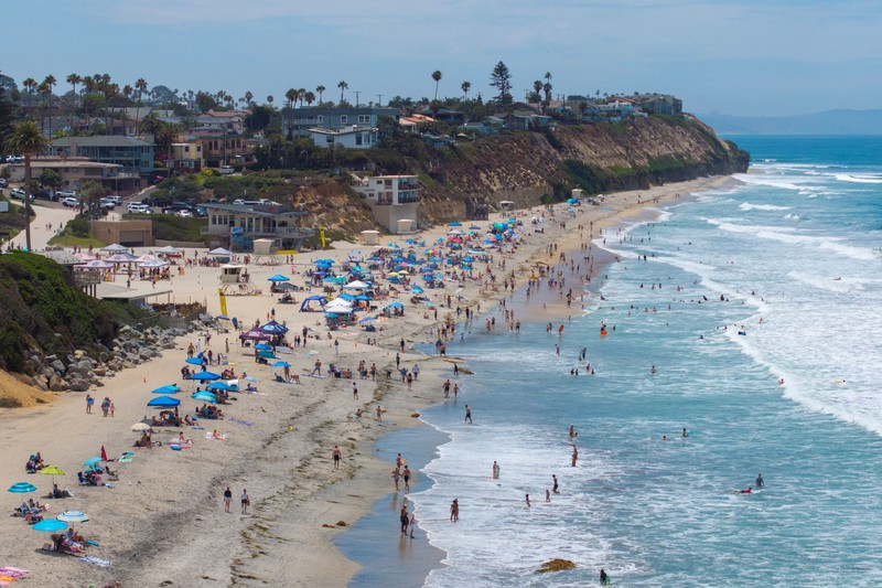 Sebuah tayangan drone memperlihatkan orang-orang menikmati air hangat di lautan sepanjang garis pantai di Encinitas, California, AS, 21 Juli 2026. (REUTERS/Mike Blake)