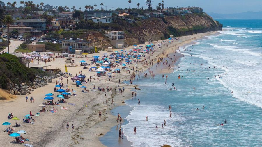 Sebuah tayangan drone memperlihatkan orang-orang menikmati air hangat di lautan sepanjang garis pantai di Encinitas, California, AS, 21 Juli 2026. (REUTERS/Mike Blake)