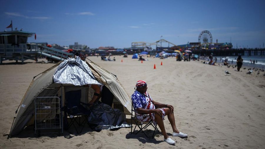 Seorang pengunjung pantai duduk sambil berjemur di sepanjang garis pantai saat cuaca panas, di Pantai Santa Monica di Santa Monica, California, AS, 17 Juli 2026.