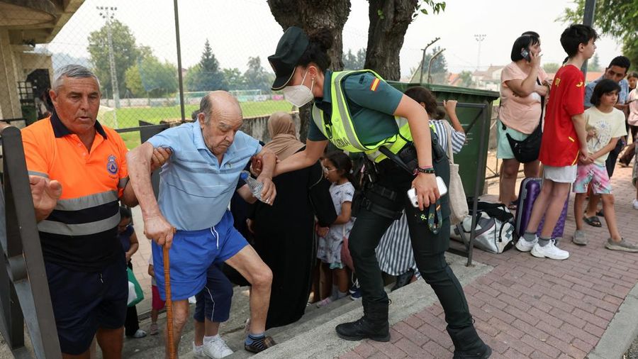 Seorang polisi wanita membantu seorang warga lanjut usia yang dievakuasi saat orang-orang berlindung sementara dari kebakaran hutan di daerah Burgohondo dan San Martin de Valdeiglesias, di arena olahraga kota di Cebreros, Avila, Spanyol, 24 Juli 2026.