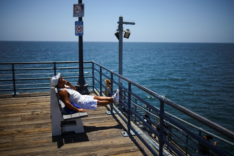 Sebuah tayangan drone memperlihatkan orang-orang menikmati air hangat di lautan sepanjang garis pantai di Encinitas, California, AS, 21 Juli 2026. (REUTERS/Mike Blake)