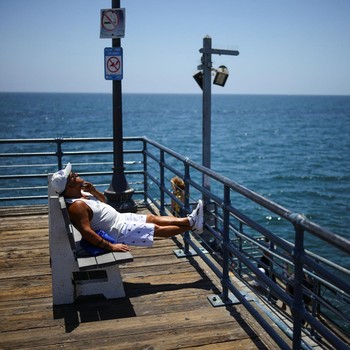 Seorang pria duduk berjemur di Dermaga Santa Monica saat cuaca panas, di Pantai Santa Monica di Santa Monica, California, AS, 17 Juli 2026. (REUTERS/Daniel Cole)