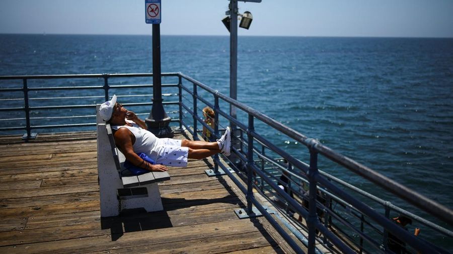 Seorang pria duduk berjemur di Dermaga Santa Monica saat cuaca panas, di Pantai Santa Monica di Santa Monica, California, AS, 17 Juli 2026.
