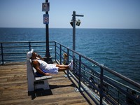 Seorang pria duduk berjemur di Dermaga Santa Monica saat cuaca panas, di Pantai Santa Monica di Santa Monica, California, AS, 17 Juli 2026. (REUTERS/Daniel Cole)