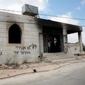 Anak-anak muda Palestina berdiri di depan sebuah masjid yang rusak, yang menurut warga Palestina dirusak oleh pemukim Israel, di Qusra dekat Nablus, di Tepi Barat yang diduduki Israel, 26 Juli 2026. Grafiti di dinding termasuk "Darah tidak membuat ka