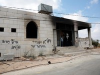 Anak-anak muda Palestina berdiri di depan sebuah masjid yang rusak, yang menurut warga Palestina dirusak oleh pemukim Israel, di Qusra dekat Nablus, di Tepi Barat yang diduduki Israel, 26 Juli 2026. Grafiti di dinding termasuk "Darah tidak membuat ka