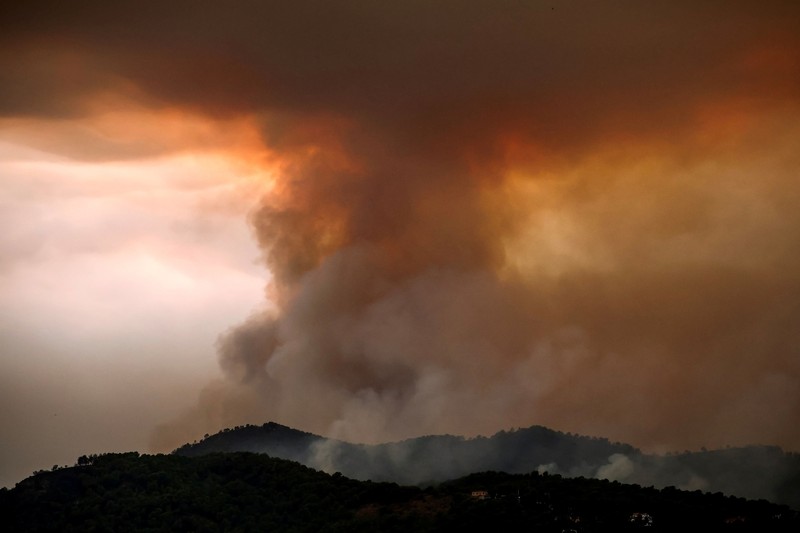 Warga dari desa-desa yang dievakuasi duduk untuk makan sambil berlindung di pusat olahraga di Moncofa, Castellon, Spanyol, 26 Juli 2026. (REUTERS/Eva Manez)