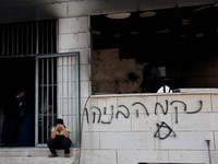 Seorang anak laki-laki Palestina duduk di dekat masjid yang rusak, yang menurut warga Palestina dirusak oleh pemukim Israel, di Qusra dekat Nablus, di Tepi Barat yang diduduki Israel, 26 Juli 2026. Grafiti di dinding bertuliskan "Balas Dendam Benayah