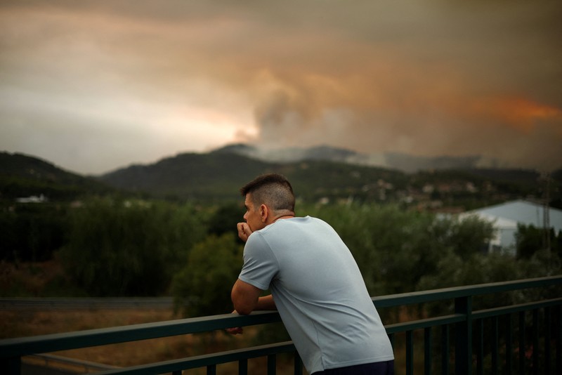 Warga dari desa-desa yang dievakuasi duduk untuk makan sambil berlindung di pusat olahraga di Moncofa, Castellon, Spanyol, 26 Juli 2026. (REUTERS/Eva Manez)
