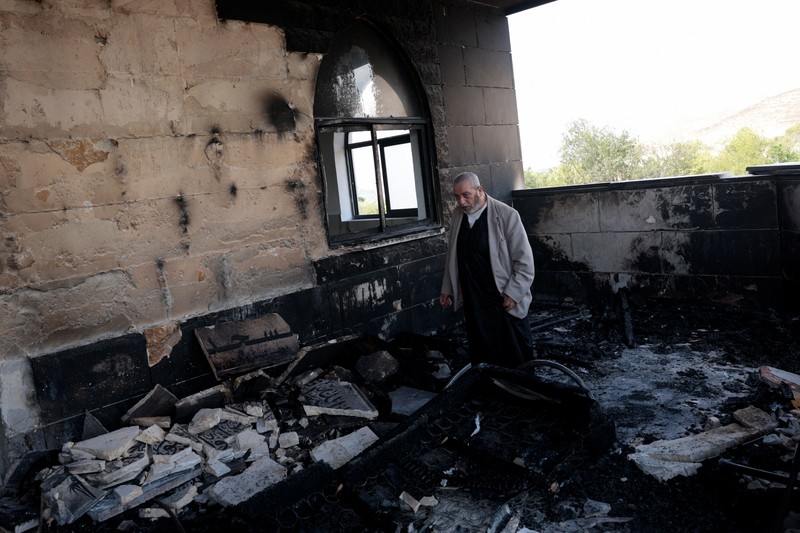 Anak-anak muda Palestina berdiri di depan sebuah masjid yang rusak, yang menurut warga Palestina dirusak oleh pemukim Israel, di Qusra dekat Nablus, di Tepi Barat yang diduduki Israel, 26 Juli 2026. Grafiti di dinding termasuk
