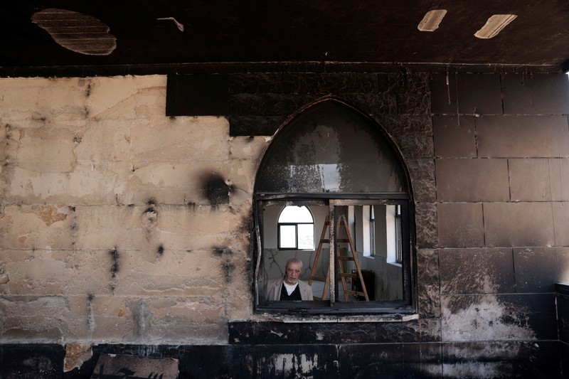 Anak-anak muda Palestina berdiri di depan sebuah masjid yang rusak, yang menurut warga Palestina dirusak oleh pemukim Israel, di Qusra dekat Nablus, di Tepi Barat yang diduduki Israel, 26 Juli 2026. Grafiti di dinding termasuk