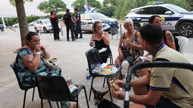 Warga dari desa-desa yang dievakuasi duduk untuk makan di pusat olahraga yang digunakan untuk menampung pengungsi, di Moncofa, Castellon, Spanyol, 26 Juli 2026.