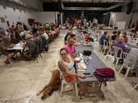 Warga dari desa-desa yang dievakuasi duduk untuk makan sambil berlindung di pusat olahraga di Moncofa, Castellon, Spanyol, 26 Juli 2026. (REUTERS/Eva Manez)
