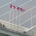 Bendera AS dan Kanada terlihat di titik tengah Jembatan Internasional Gordie Howe yang menghubungkan Windsor, Ontario ke Detroit, Michigan, AS, di Windsor, Ontario, Kanada, 27 Juli 2026. (REUTERS/Rebecca Cook)