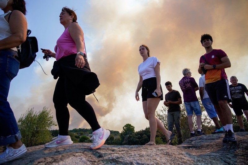 Seorang pria dan anjingnya melihat kebakaran hutan di pegunungan di Onda, Spanyol, 27 Juli 2026. (REUTERS/Pedro Nunes)