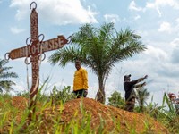 Charles Mambo, the supervisor at the Ceca-20 cemetery, flanked by Moise Mund'wa, the assistant warden of the cemetery, talks near graves during an interview with Reuters, as aid agencies intensify efforts to contain an Ebola outbreak caused by the Bu