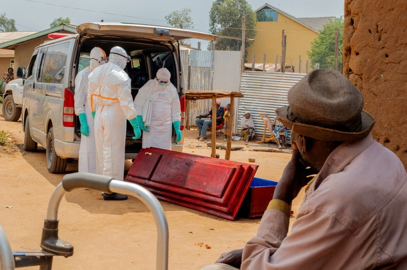 Charles Mambo, the supervisor at the Ceca-20 cemetery, flanked by Moise Mund'wa, the assistant warden of the cemetery, talks near graves during an interview with Reuters, as aid agencies intensify efforts to contain an Ebola outbreak caused by the Bundibugyo virus, in the Ebola hit Mungwalu, Djugu Territory of Ituri province, Democratic Republic of Congo, July 14, 2026. REUTERS/Gradel Muyisa Mumbere     TPX IMAGES OF THE DAY