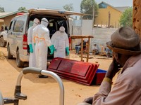 Members of the Civil Protection, a local community-based team that works to help mitigate the spread of the Ebola virus and ensure burials happen safely and quickly, wearing personal protective equipment (PPE), handle a wooden coffin before loading t