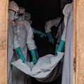 Members of the Civil Protection, a local, community-based team that helps lower resistance and ensures burials happen safely and quickly, while wearing personal protective equipment (PPE), carry a body bag with the remains of an unidentified man who,