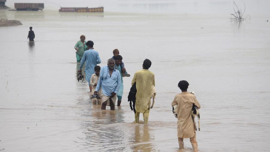 Orang-orang menyeberangi jalan yang tergenang air akibat hujan monsun di Muridke, Pakistan, 28 Juli 2026.